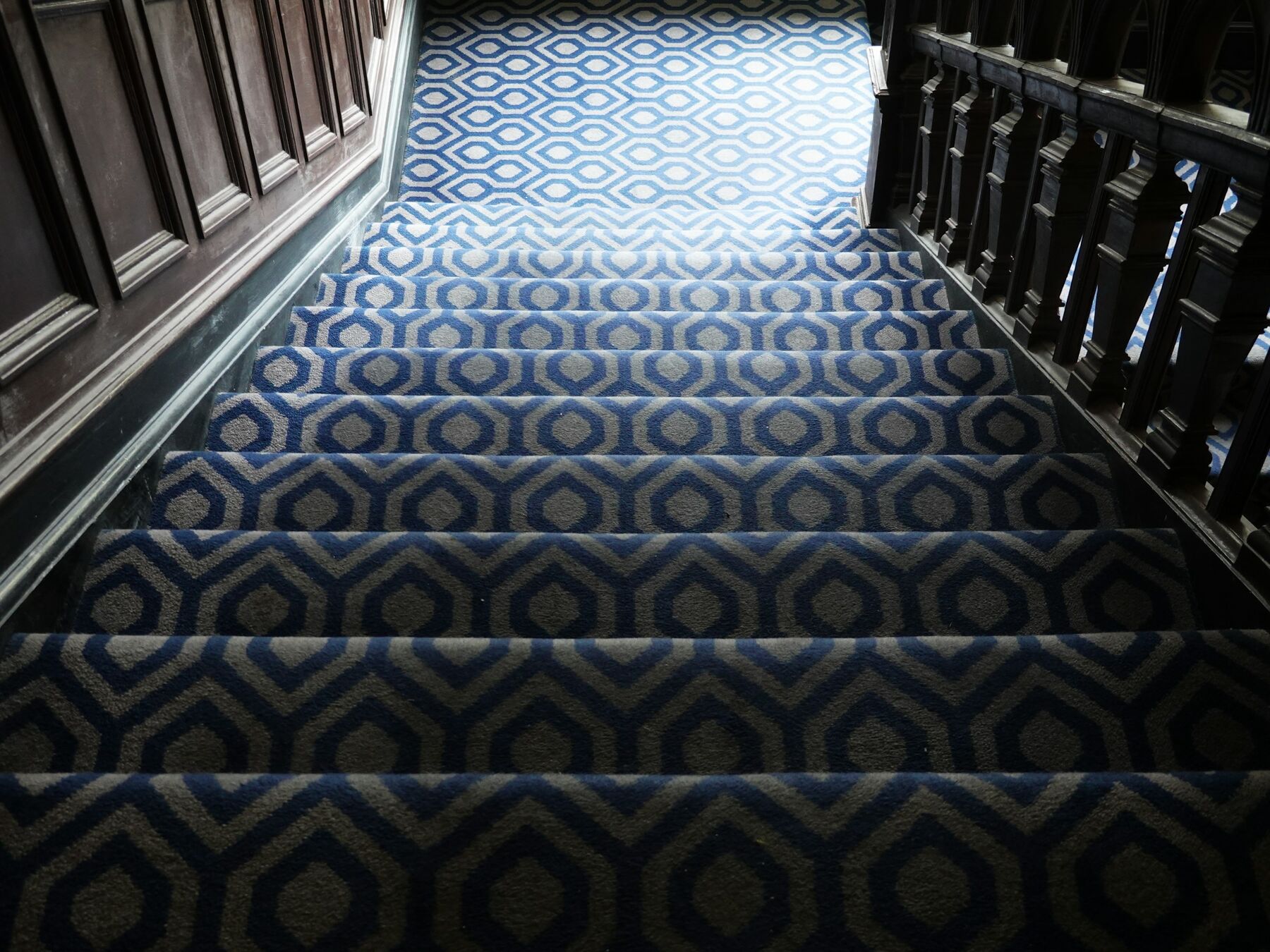 Carpeted staircase with a patterned runner and dark timber banisters
